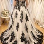 Rückenansicht eines schwarz-weißen Brautkleids mit ausladender Schleppe, detailreicher schwarzer Spitze und Off-Shoulder-Trägern. LAFANTA Dark Couture.