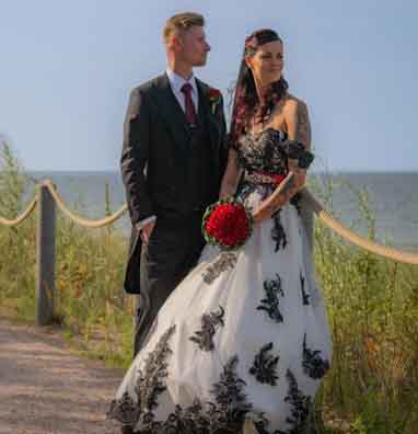Brautpaar am Meer – Braut in schwarz-weißem Hochzeitskleid mit roten Akzenten